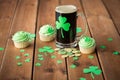 Shamrock on glass of beer, green cupcake and coins Royalty Free Stock Photo