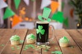 Shamrock on glass of beer, green cupcakes and coins Royalty Free Stock Photo