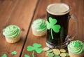 Shamrock on glass of beer, green cupcakes and coins Royalty Free Stock Photo