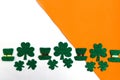 Shamrocks and leprechaun hats pattern on white and orange background. Patrick Day symbols on Ireland flag