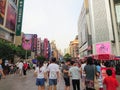 A busy scene of Nanjing Road Walkway where visitors walk and shop among various department stores and skyscrapers