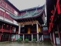 A traditional Chinese architectural-style performance stage in Yuyuan Garden with lanterns hanging around it on a rainy