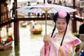 Shanghai, China - May, 2019: Chinese beautiful asian woman in national dress and umbrella against Shanghai Zhujiajiao ancient Town