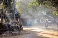 Sun rays falling on a bike riding through a dusty street in the town of Bolpur