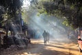 Sun rays falling on a bike riding through a dusty street in the town of Bolpur