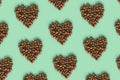 Shape heart from coffee beans on mint color background, roasted brown coffee berries, trendy design geometric pattern