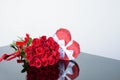 Shaped heart gift box and bouquet red classic roses on a mirror surface. Festive floristry. Gift to a woman. Sample