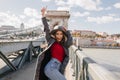 Shapely blissful girl in red sweater dancing on bridge on blur city background in autumn morning. Outdoor photo of happy Royalty Free Stock Photo