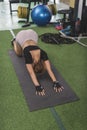 A shapely young asian woman does a variant of the child's pose stretch. Doing yoga or warming up for a workout at the gym Royalty Free Stock Photo