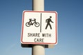 Share with care warning sign on a shared path for pedestrians and cyclists against a clear blue sky background Royalty Free Stock Photo