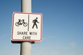 Share with care warning sign on a shared path for pedestrians and cyclists against a clear blue sky background Royalty Free Stock Photo