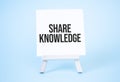 SHARE KNOWLEDGE sign on the white paper. easel on the blue background