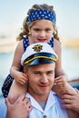 They share an unbreakable bond. Portrait of a father in a navy uniform carrying his little girl on his shoulders.