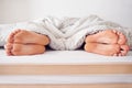 Sharing a bed. a couples feet poking out from under a duvet. Royalty Free Stock Photo