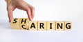 Sharing is caring symbol. Businessman turns wooden cubes and changes the word `sharing` to `caring`. Beautiful white table, wh