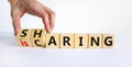 Sharing is caring symbol. Businessman turns wooden cubes with words `sharing is caring`. Beautiful white table, white background