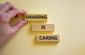 Sharing is caring symbol. Wooden blocks with words `Sharing is caring` on beautiful white background. Businessman hand. Business