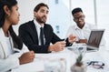 Sharing details of his analysis with the team. a young businessman having a meeting with his colleagues in an office. Royalty Free Stock Photo