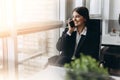 Sharing good business news. Attractive young woman talking on the mobile phone and smiling while sitting at her working place in Royalty Free Stock Photo