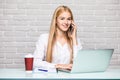 Sharing good business news. Attractive young woman talking on the mobile phone and smiling while sitting at her working place in o Royalty Free Stock Photo