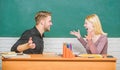 Sharing good news. Happy couple studying in classroom. Teacher and schoolmaster sitting at desk. Handsome man and pretty Royalty Free Stock Photo