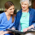 Sharing her memories. a resident and a nurse looking through a photo album. Royalty Free Stock Photo