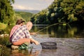 Sharing his secrets. Transferring knowledge. Friends spend nice time riverside. Experienced fisherman show tips to son Royalty Free Stock Photo