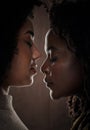 Sharing an intimate moment. a beautiful young female couple posing in studio against a dark background. Royalty Free Stock Photo