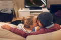 Sharing a kiss. an affectionate young couple stealing a kiss while watching television.