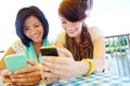 Sharing a love of technology. Two teenage girls sitting outside texting on their cellphones. Royalty Free Stock Photo