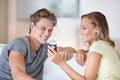 Sharing memories. A young couple looking at their cellphone in their living room. Royalty Free Stock Photo