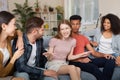 Sharing news. Young beautiful girl discussing something with best friends and smiling while sitting together on the sofa Royalty Free Stock Photo