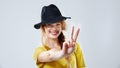 Sharing the peace. Cropped studio portrait of a beautiful young woman wearing a black hat showing the peace sign. Royalty Free Stock Photo