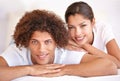 Sharing a relaxed morning...Portrait of a close young couple lying down in bed and smiling at the camera. Royalty Free Stock Photo