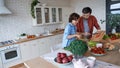 Sharing skills. Young dad and his little happy son cutting preparing a vegetarian salad together in the modern kitchen