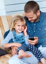 Sharing some oldies with a newie. an adorable little girl sitting on the sofa sharing headphones with her father. Royalty Free Stock Photo