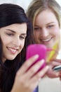 Sharing their playlists...Two young female friends listening to music on a mp3 player together. Royalty Free Stock Photo