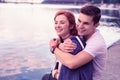 Strong smiling guy tightly hugging his pretty ginger girlfriend