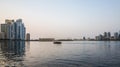 Sharjah. Summer 2016. Evening cityscape with the boat in the Persian Gulf and city architecture.