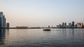 Sharjah. Summer 2016. Evening cityscape with the boat in the Persian Gulf and city architecture.