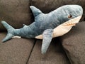 Shark, a big stuffed animal lying on a dark fabric couch. The gray sharks fall prey with teeth