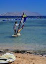 Sharm el-Sheikh, Egypt - March 14, 2018. A girl runs a board with a sail on the mast due to the inclination and turn of the mast.