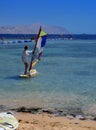 Sharm el-Sheikh, Egypt - March 14, 2018. A girl runs a board with a sail on the mast due to the inclination and turn of the mast.