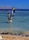 Sharm el-Sheikh, Egypt - March 14, 2018. A girl runs a board with a sail on the mast due to the inclination and turn of the mast.