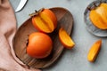 Sharon persimmon fruit and wedges or date-plum on wooden plate
