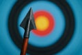 Close-up of an arrowhead with a colorful target in the background during an archery practice session Royalty Free Stock Photo