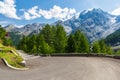 Sharp bend in Stelvio Pass in stunning sunlit Dolomites. Picturesque view of the snow capped mountain range above the winding