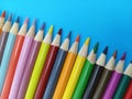 Sharp colorful pencil crayons lined up on a blue background