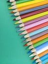 Sharp colorful pencil crayons lined up on a green background