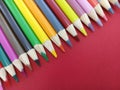 Sharp colorful pencil crayons lined up on a red background